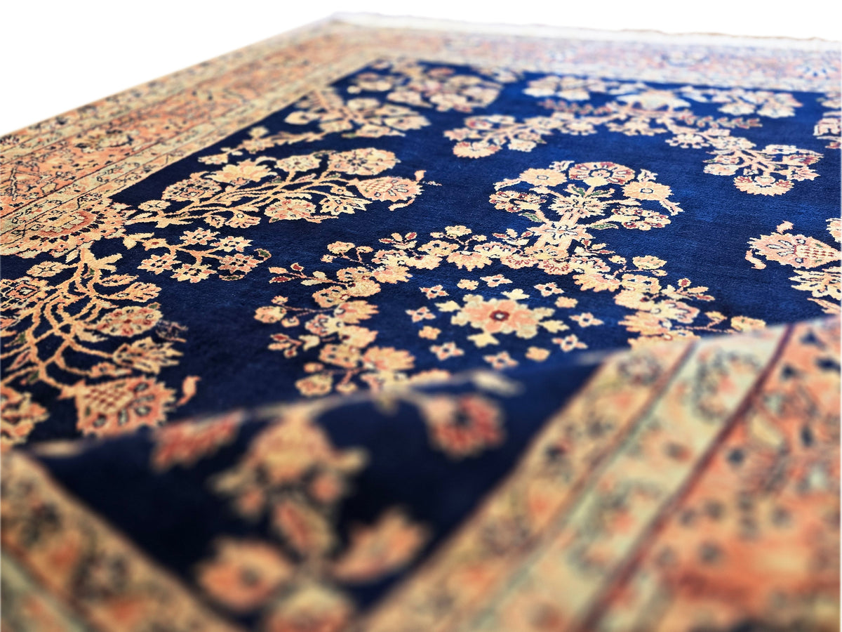 Sarouk rug close-up: navy ground with floral medallion and rust-beige border, textured pile
