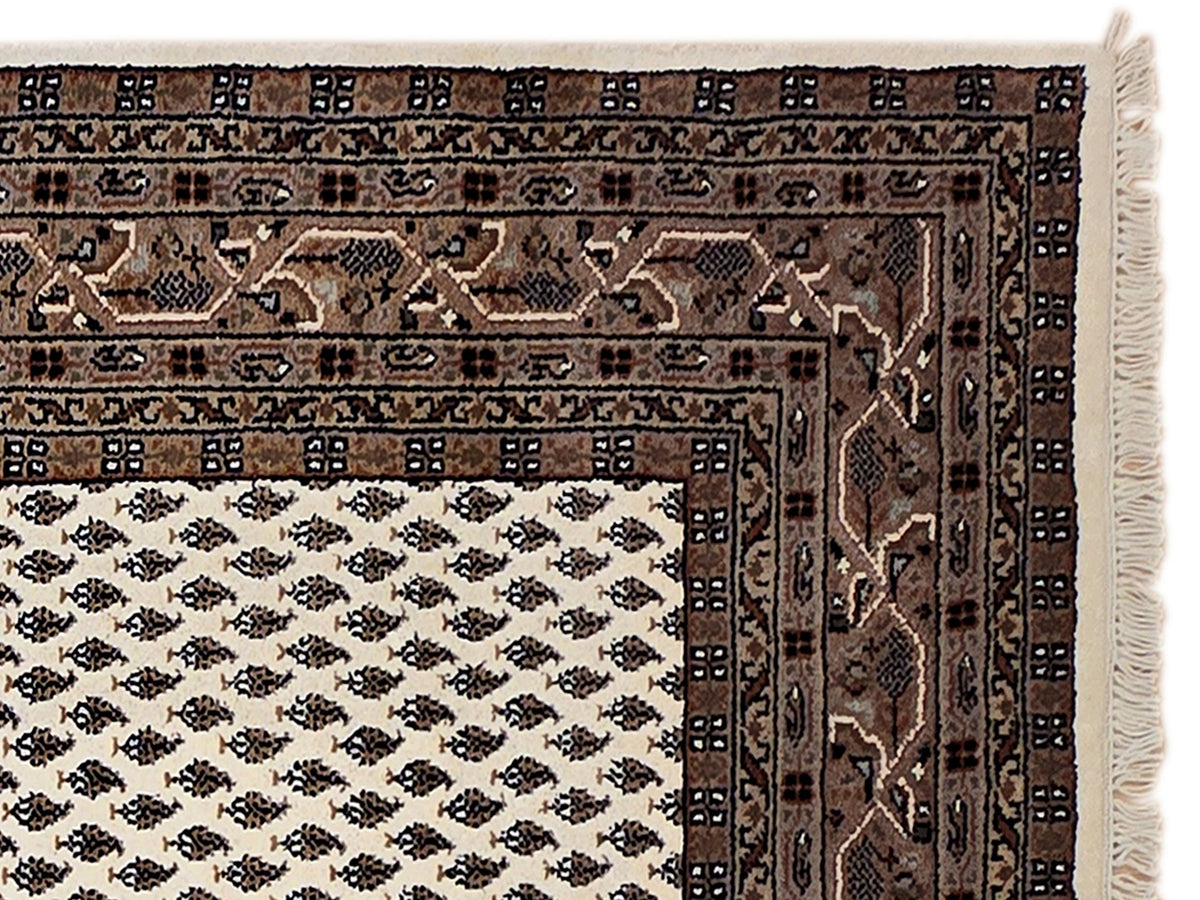 Geometric rug border close-up with dark pattern and cream fringe on the edge