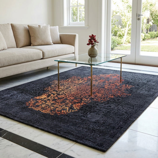 Dark navy rug with orange-red abstract center medallion, in living room setting