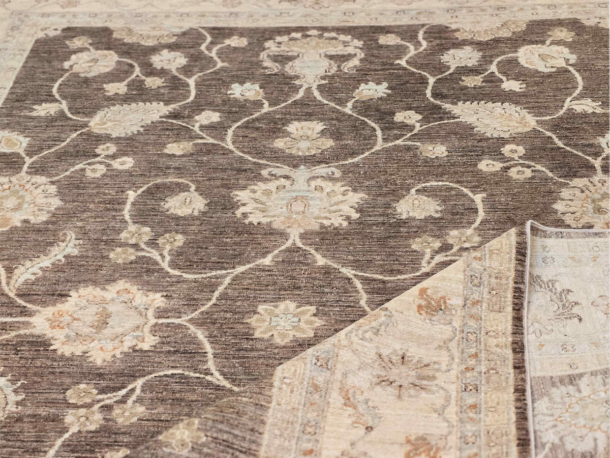 Afghan rug close-up: dark brown field with cream floral vines and small medallions