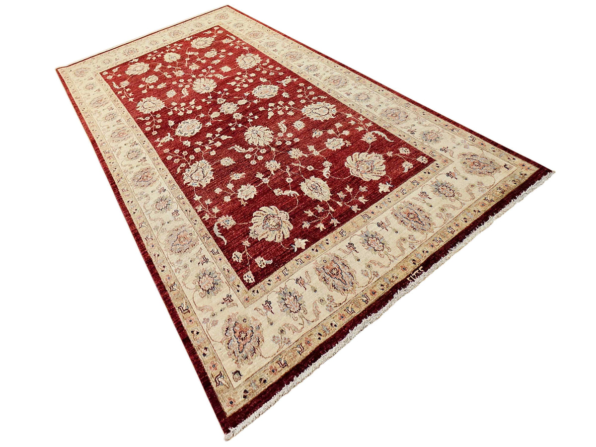 Rectangular red rug with cream patterned border and scattered floral motifs