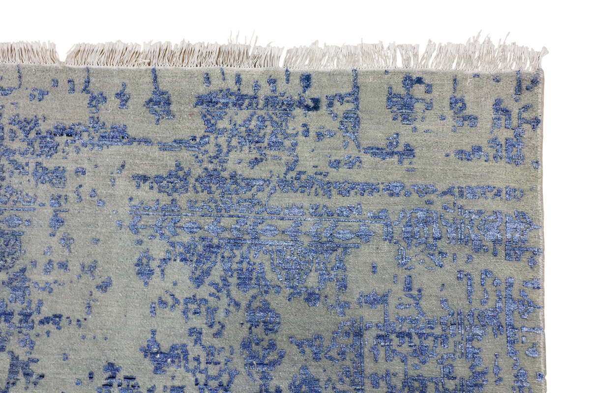 Blue mist rug border close-up with distressed motif pattern and short fringed edge.