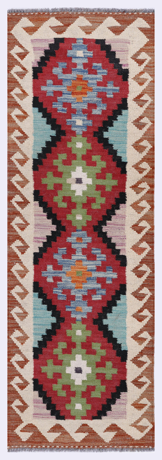 Red and blue geometric kilim rug with central medallion and zigzag border, long narrow.