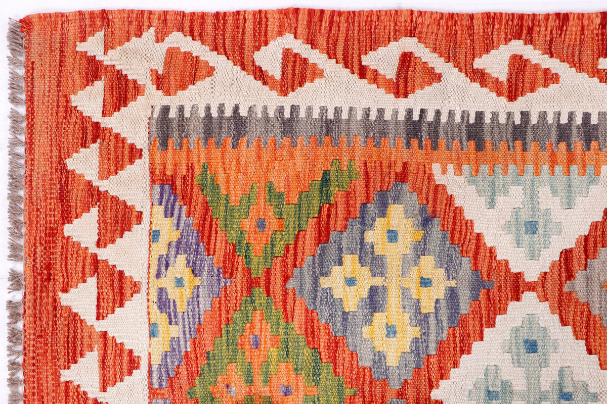 Close-up orange kilim rug with floral-like medallions, green and blue accents