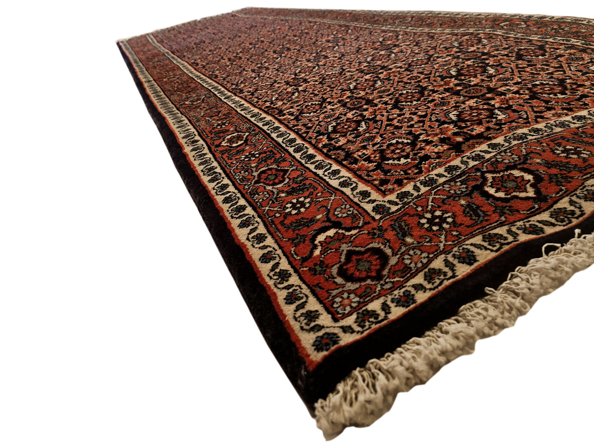 Bidjar rug with dark red center medallions, navy accents, beige border, and fringe.