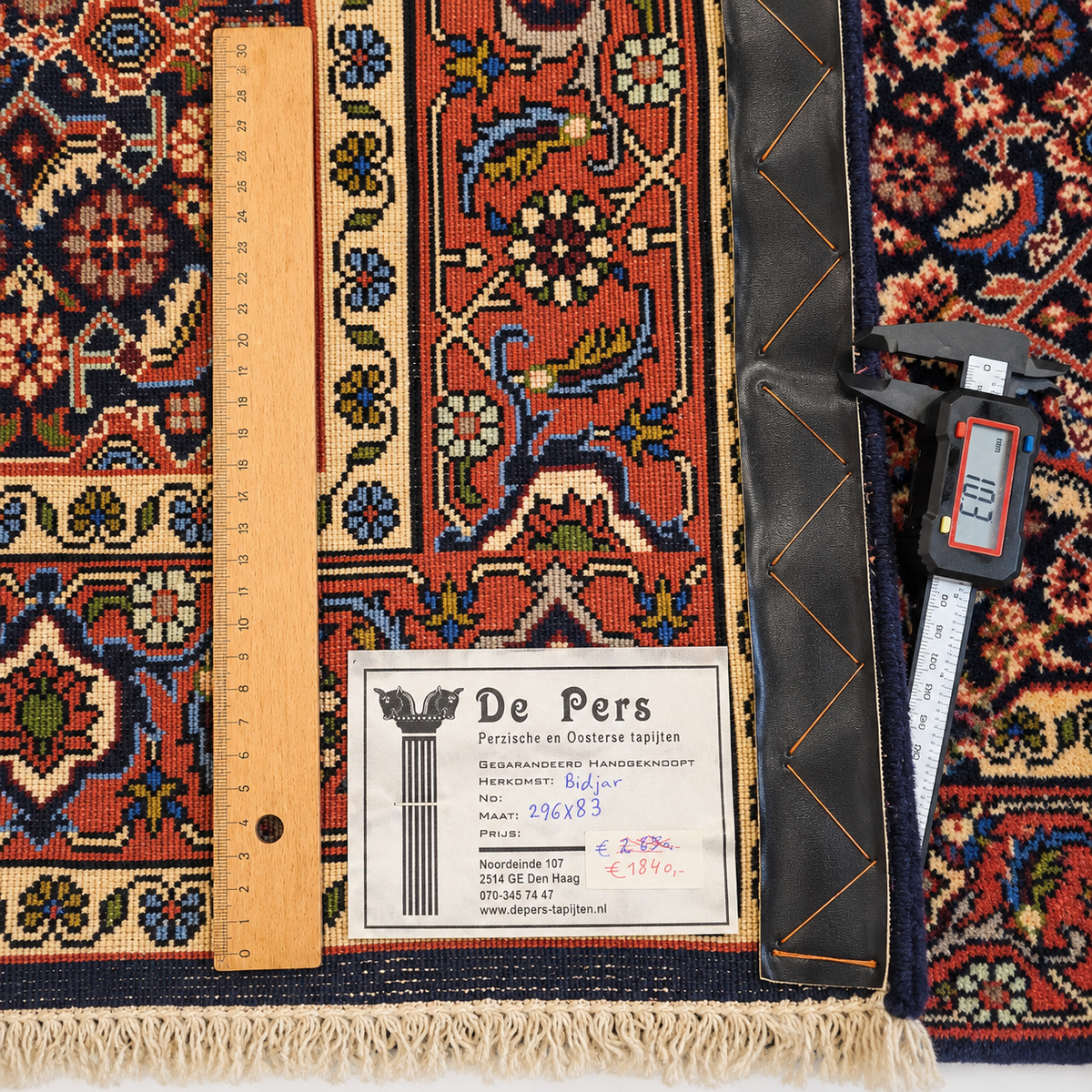 Bidjar rug detail showing weave, fringe, and size label with measuring tape.