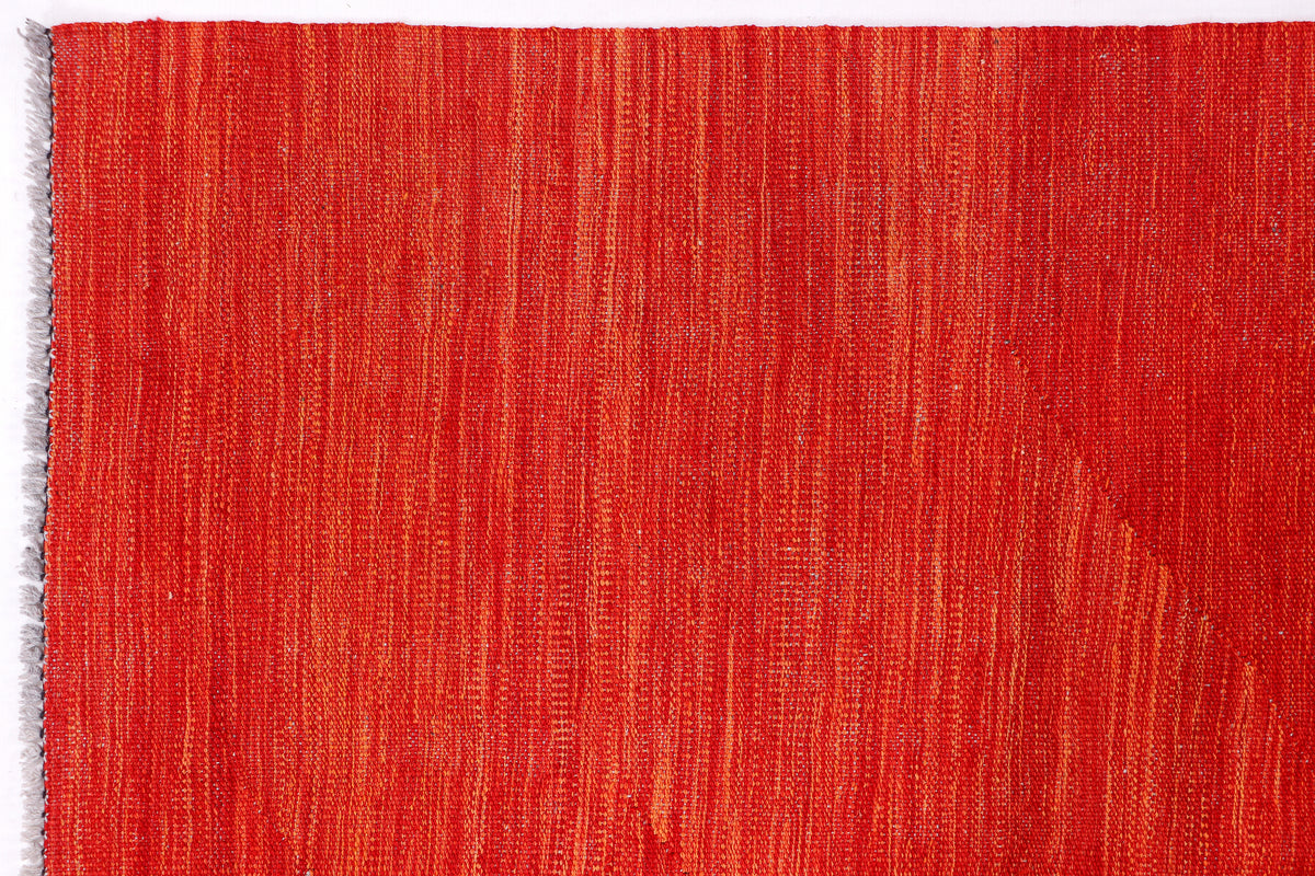 Red rug with finished border and visible fringe along the edge