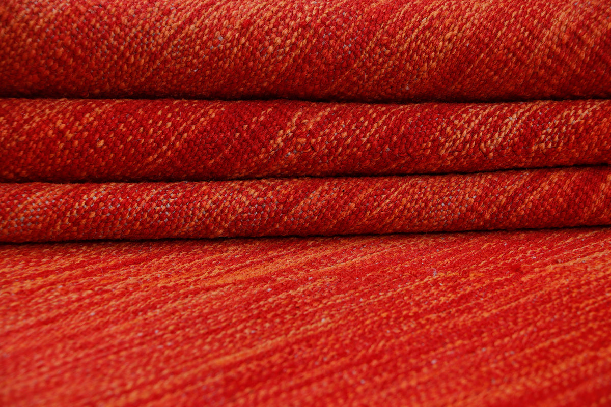 Red kilim-style rug with textured weave and subtle pattern