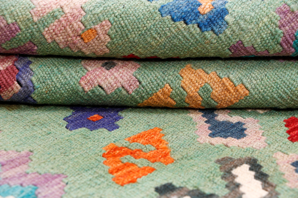Green kilim rug flatweave texture with layered multicolor flower and star motifs