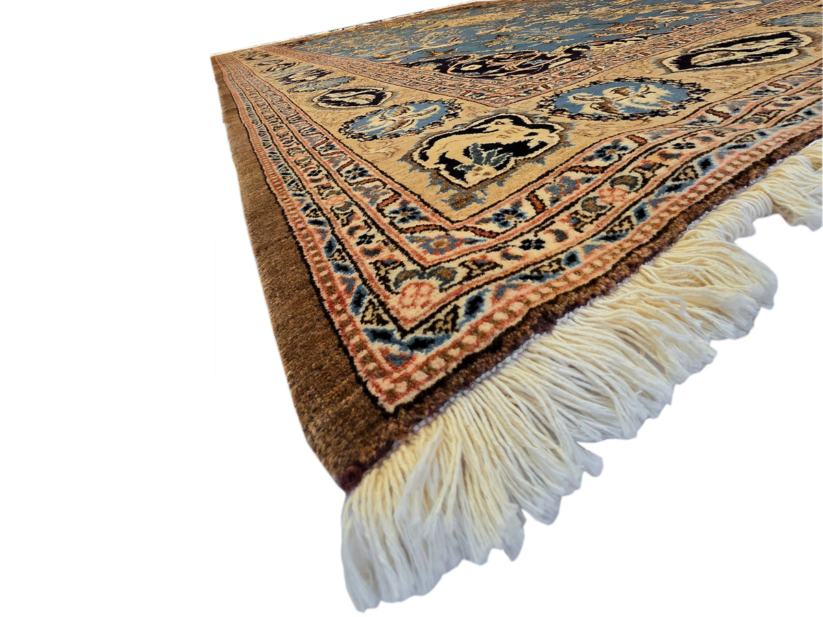 Corner view of blue and brown patterned rug with thick cream fringe