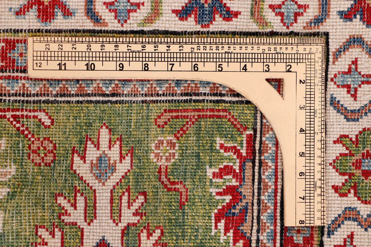 Green rug with red, blue, and cream geometric floral motifs and bordered design
