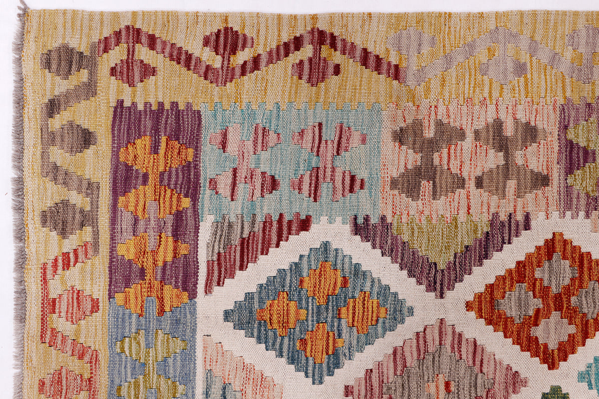 Beige kilim rug close-up showing multicolor floral and diamond geometric pattern