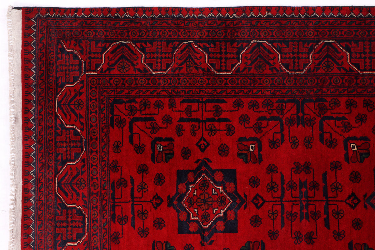 Red rug detail showing central diamond medallion and repeating border motifs