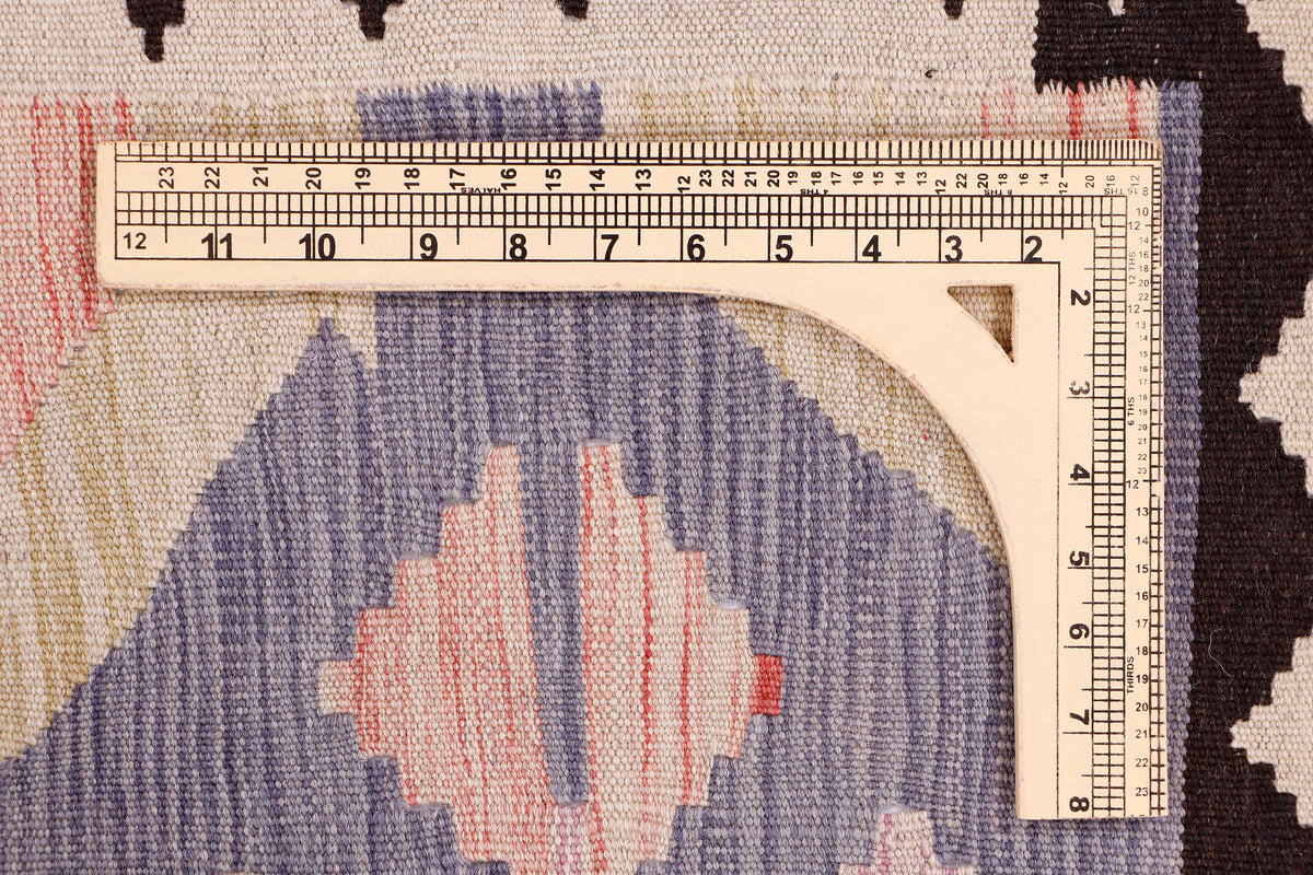 Kilim rug weave close-up with purple geometric field, cream accents, and measuring tape.
