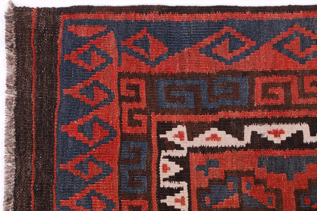 Close-up kilim rug with red and dark blue motifs and fringe edging