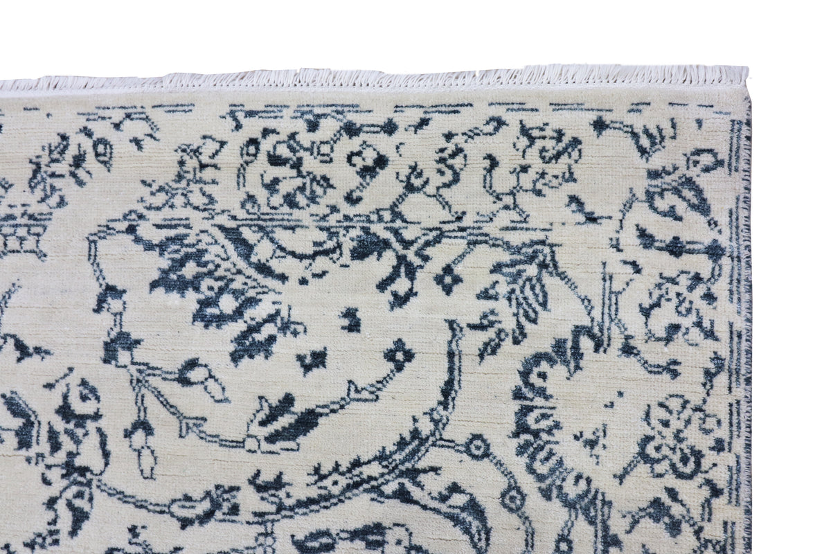 Off-white rug with dark blue intricate scroll-and-floral pattern and stitched border