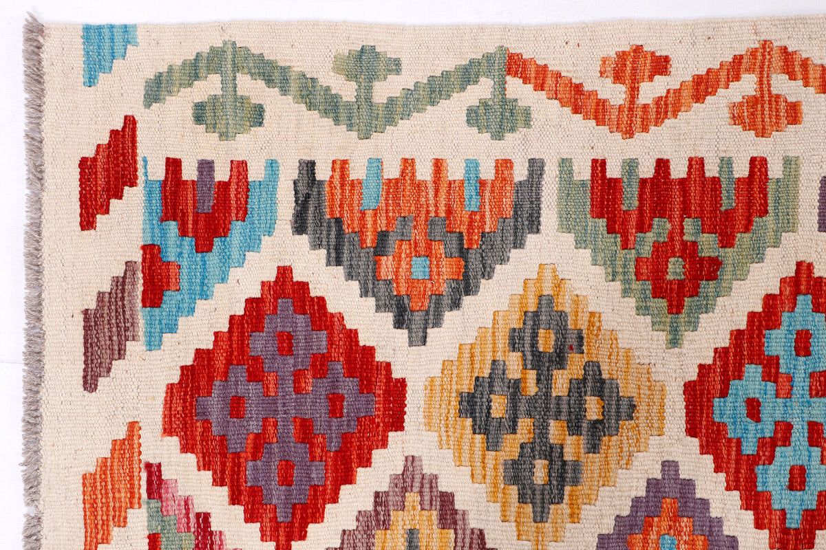 Kilim rug close-up with multicolor diamond and chevron motifs on cream