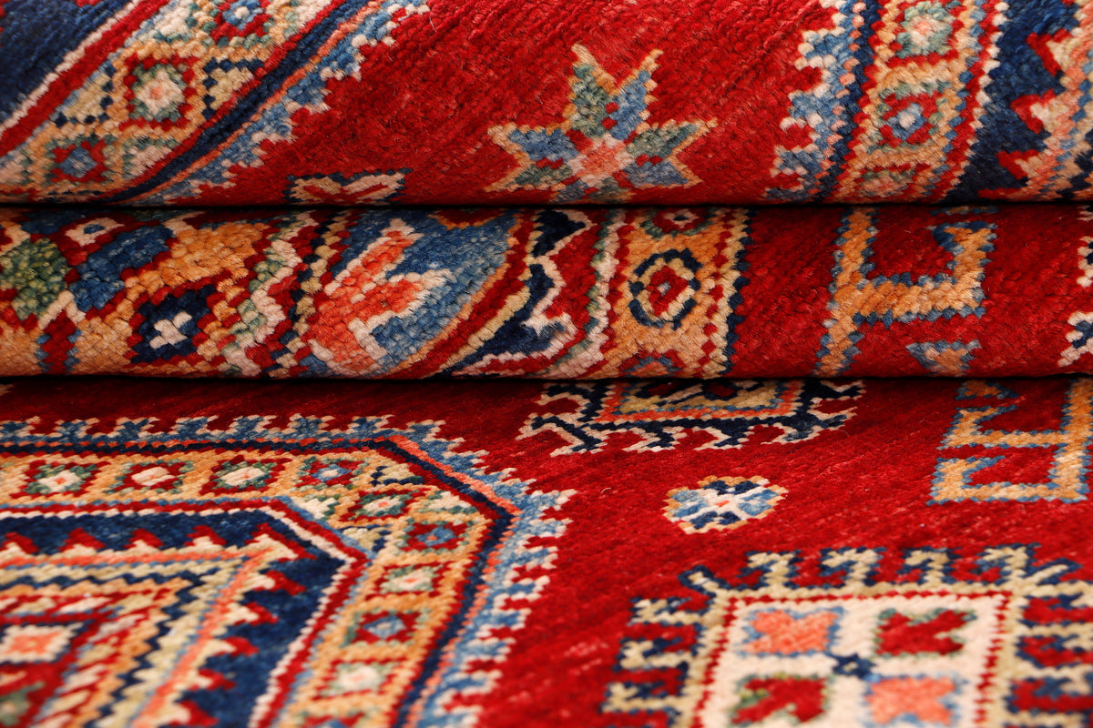 Close-up of red rug pile and multicolor geometric design along fold