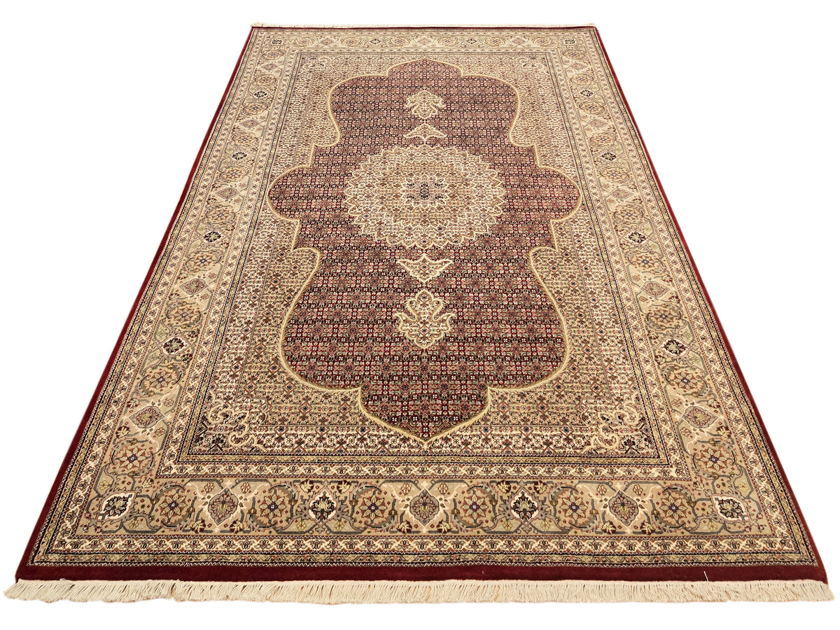 Patterned area rug with dark red and beige arch motif and ornate border