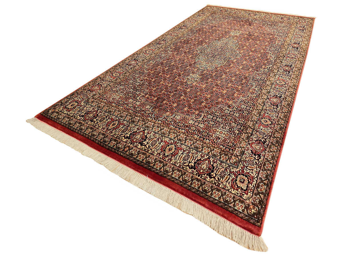 Bidjar rug with rust red field, intricate motifs, dark border, and cream fringe along edges.