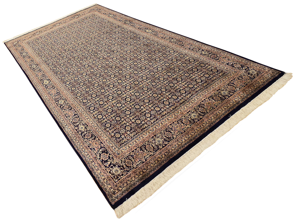 Bidjar-style area rug with dark blue field, ornate border, and cream fringe edging