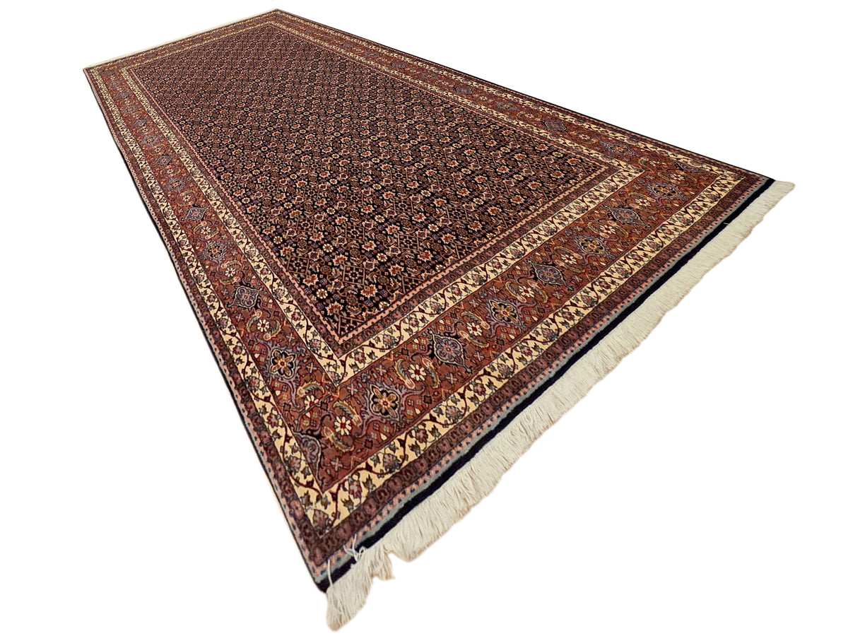 Rust and dark brown patterned rug with cream border lines and short fringe