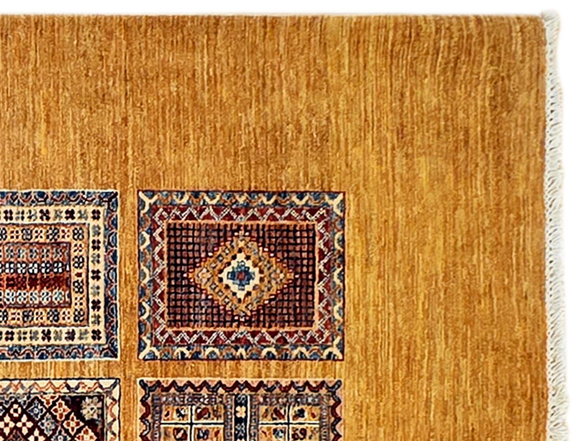 Close-up of warm gold area rug with partial multicolor pattern and short fringed border
