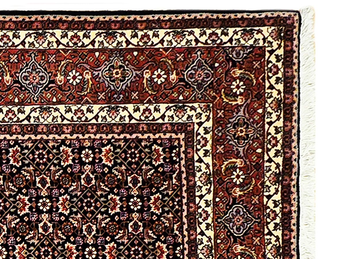 Close-up corner of geometric rug with ivory cartouches and dark red details
