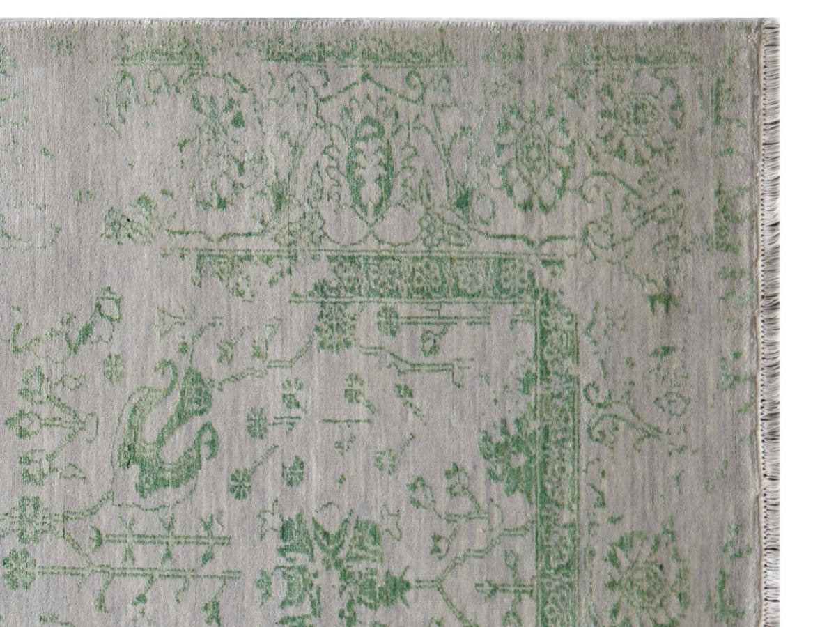 Light gray rug corner with green decorative pattern and fringed edge detail