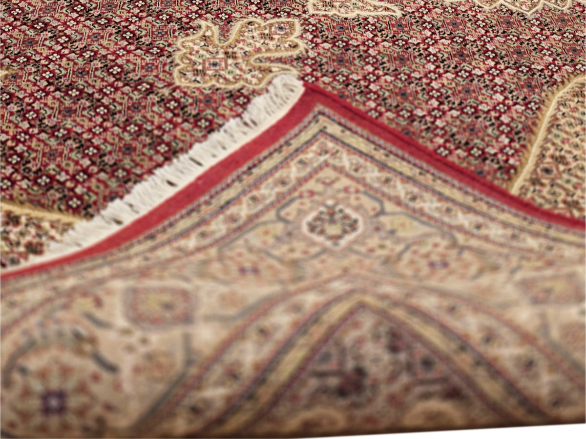 Close-up patterned area rug with red field and cream border medallion accents