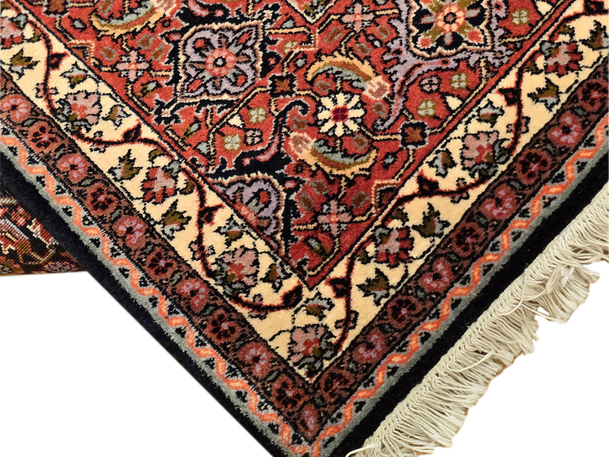 Corner detail rug with red-and-cream floral diamonds and light tassel fringe