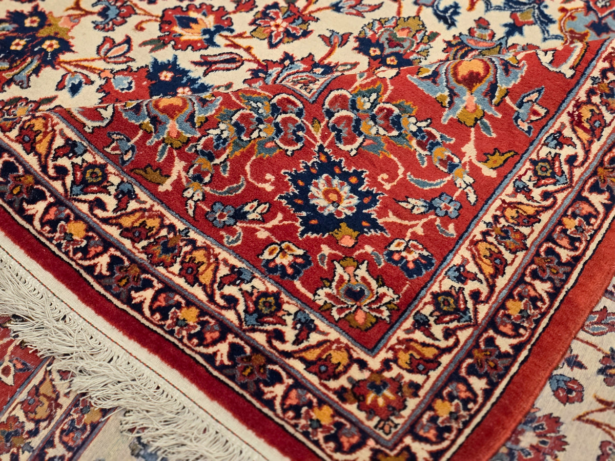 Close-up of red floral patterned rug with blue and cream accents and fringed corner