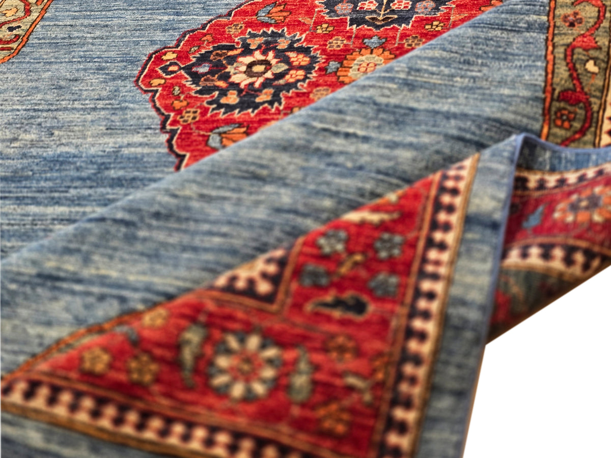 Close-up view of blue rug with red corner medallion and detailed trim border.