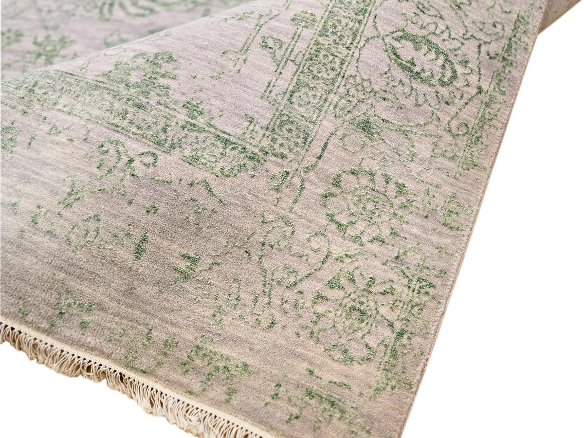 Light gray rug with green motif field and beige fringe along the border