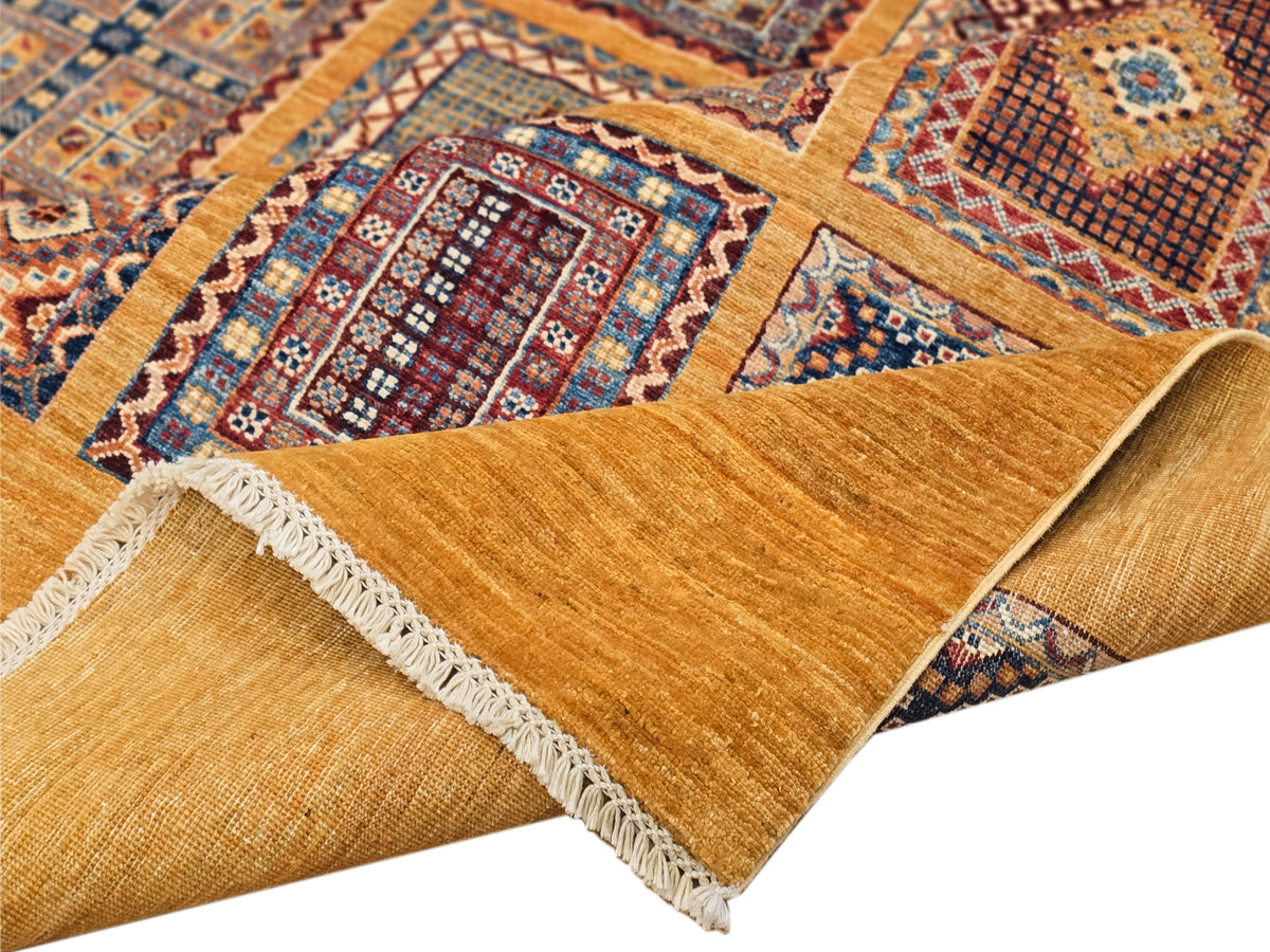 Folded area rug corner with warm gold pile, multicolor medallion pattern, and fringe along edge