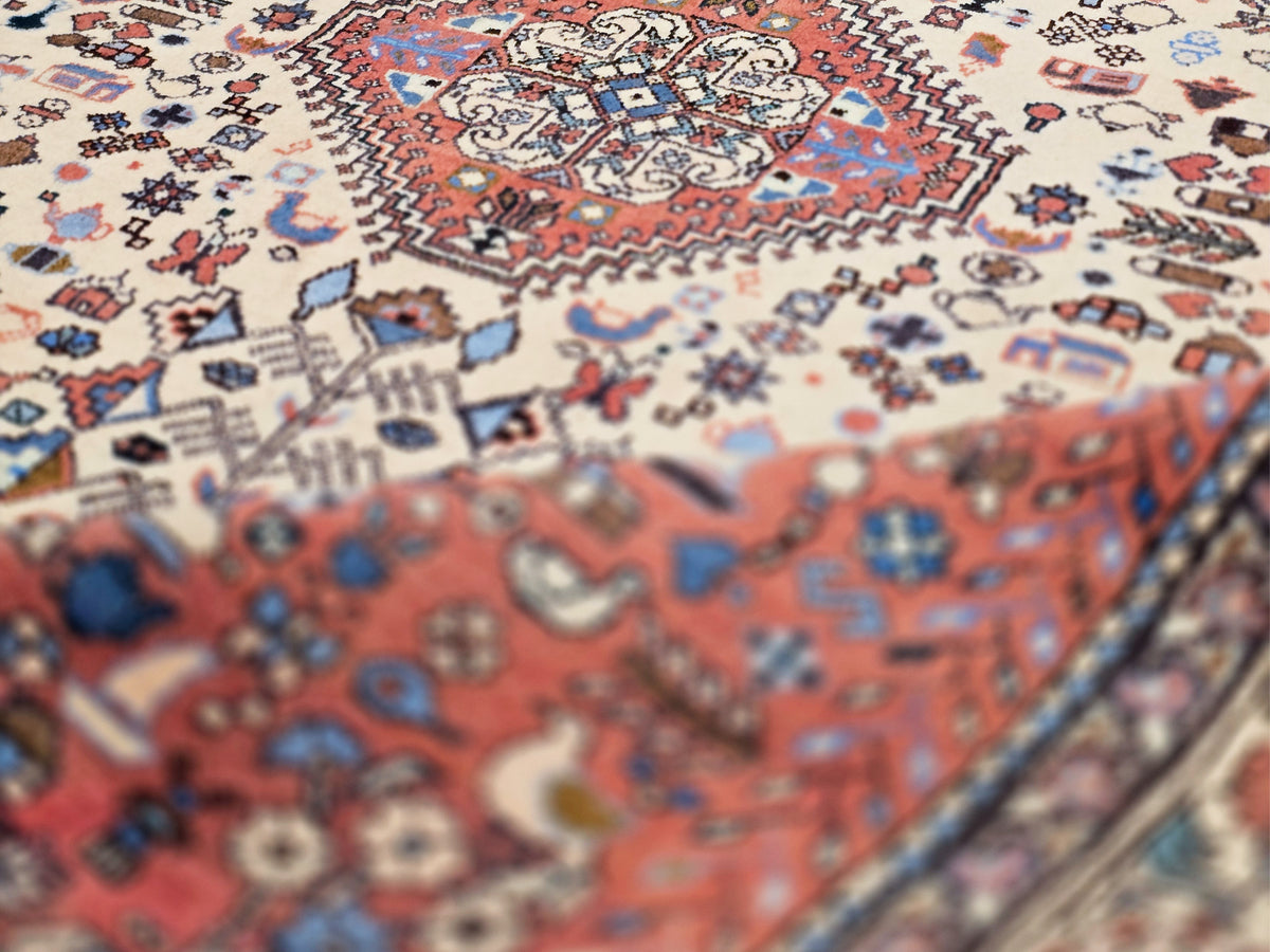 Rug surface close-up with red and blue motifs on cream ground, fine detailed pattern