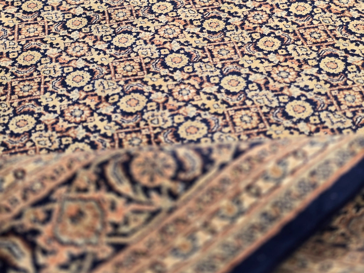 Close-up of rug pile showing intricate navy and tan floral motifs and texture