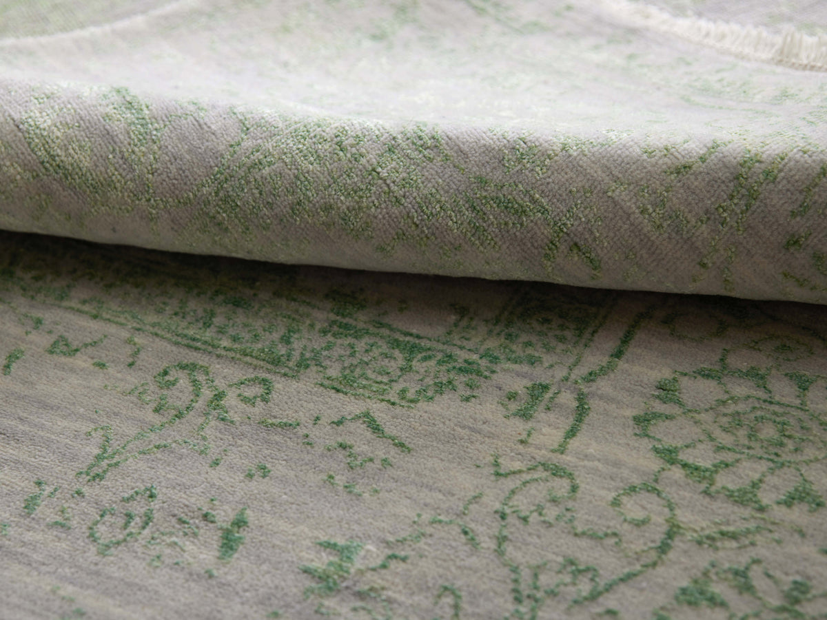 Light gray rug with green ornamental pattern, close-up of woven texture