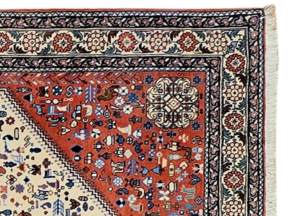 Close-up of rug border with navy, red, and cream repeating motifs and textured fringe