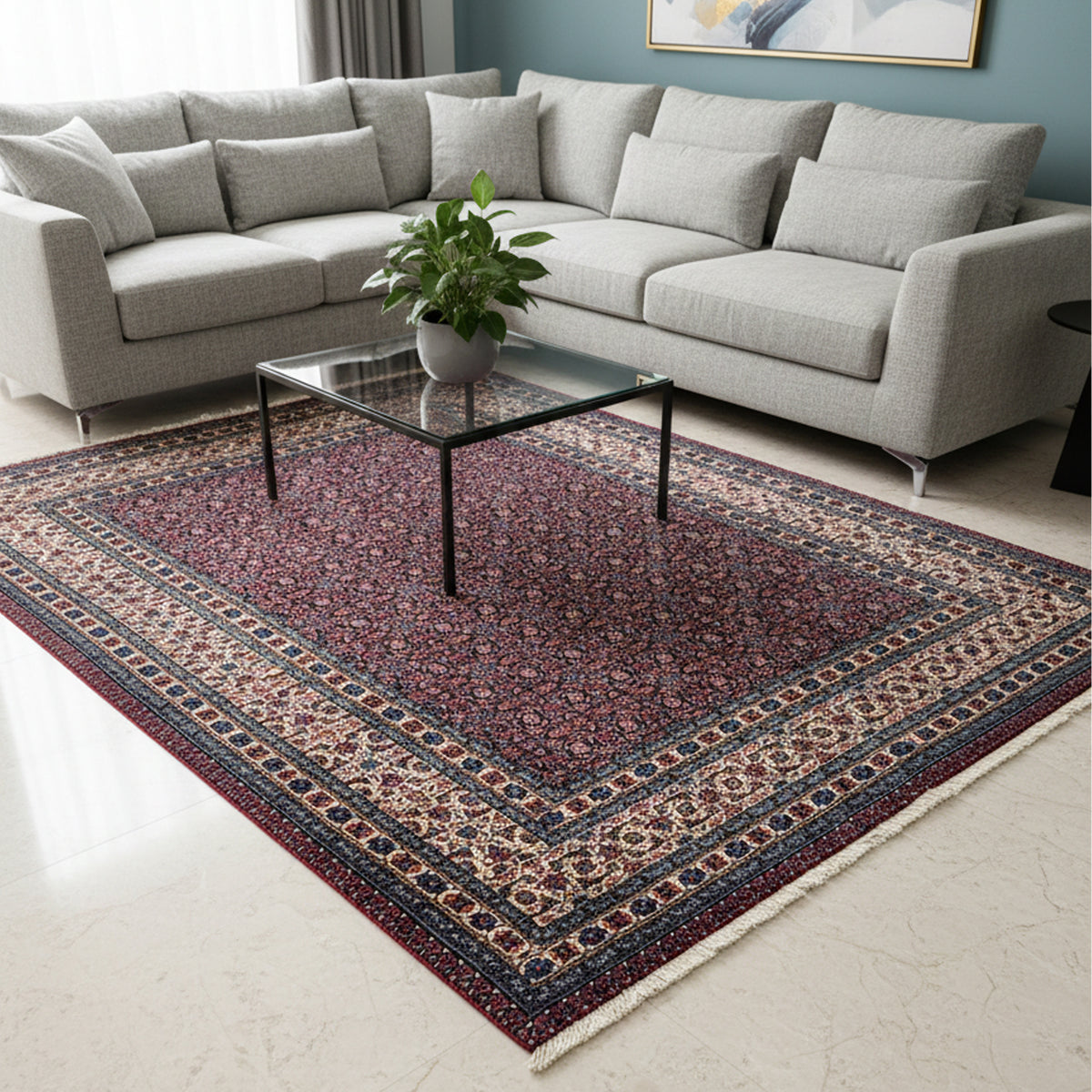 Rectangular area rug with red floral center medallion and blue geometric edging.