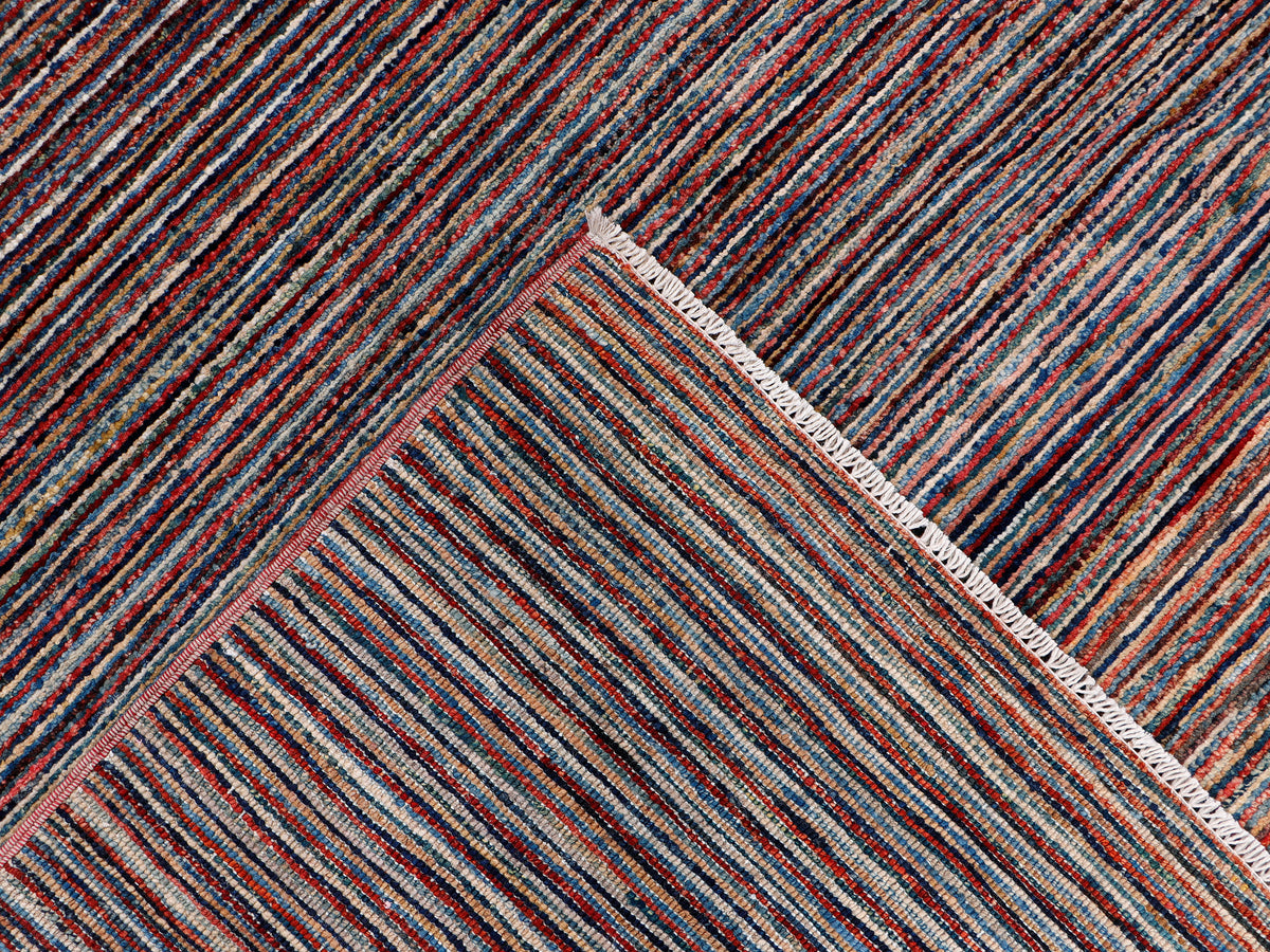 Multicolor striped rug corner detail with light border trim, flat weave.
