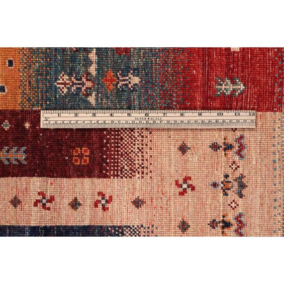 Rug close-up with red and beige fields and small blue geometric motifs