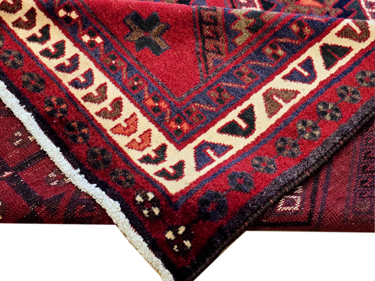 Red and navy geometric rug corner with cream border and detailed motifs