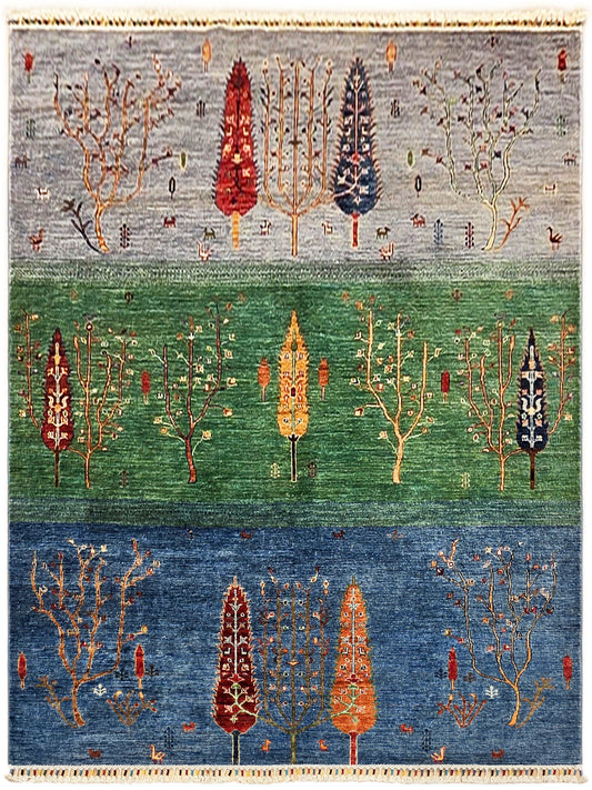 Blue and green area rug with stylized tree designs and beige fringed border.
