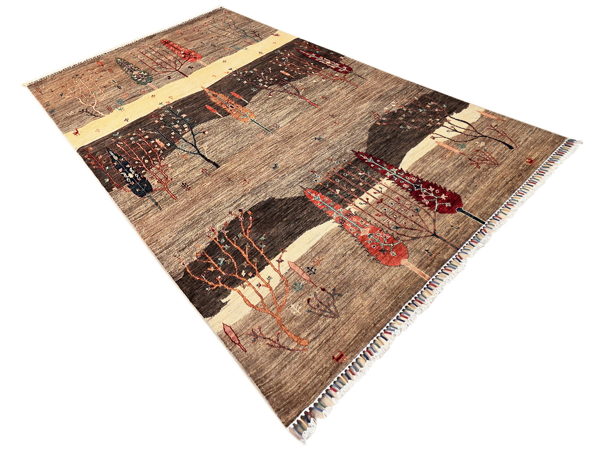 Patterned area rug, diagonal view with brown, cream, red and dark tree designs, fringes