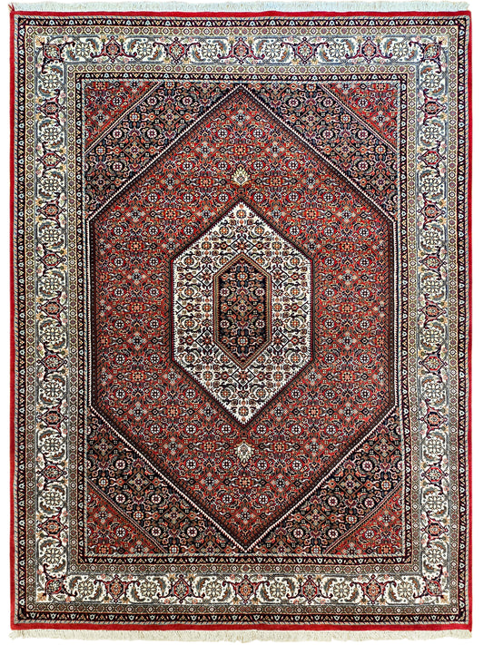 Ornate red and cream rug with diamond medallion, navy accents, and fringed edge