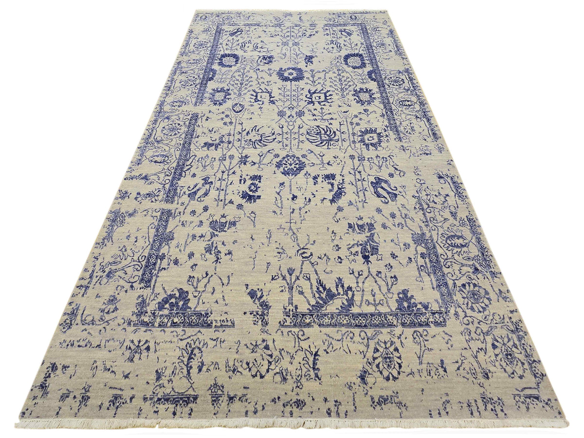 Beige and blue patterned area rug with central motifs and wide border, isolated view.