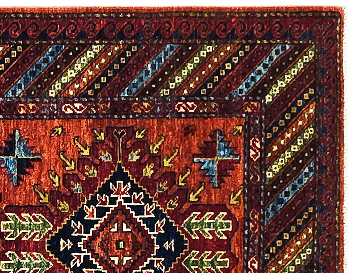 Karkahi rug close-up: red-orange field with multicolor geometric motifs and dark border
