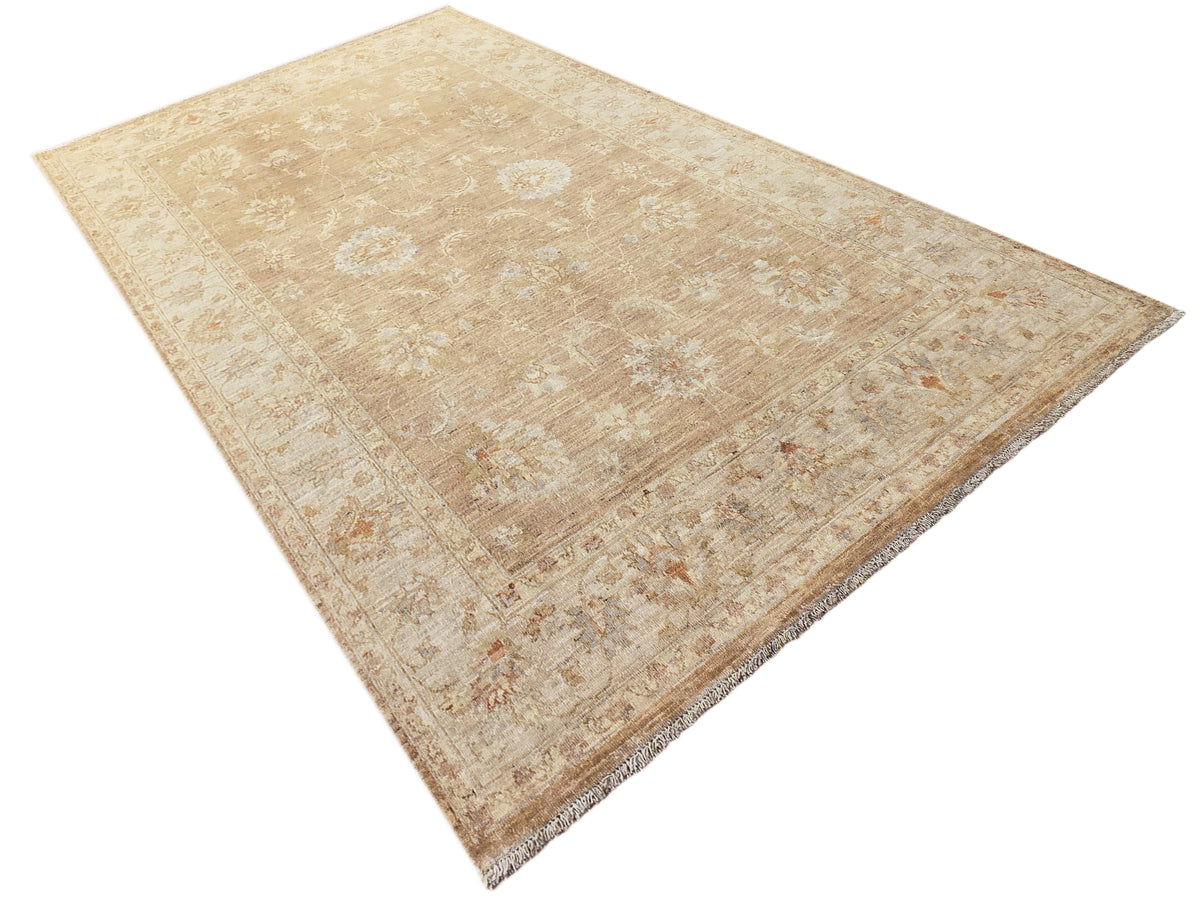 Tan-beige area rug with distressed floral and medallion pattern and fringed edge