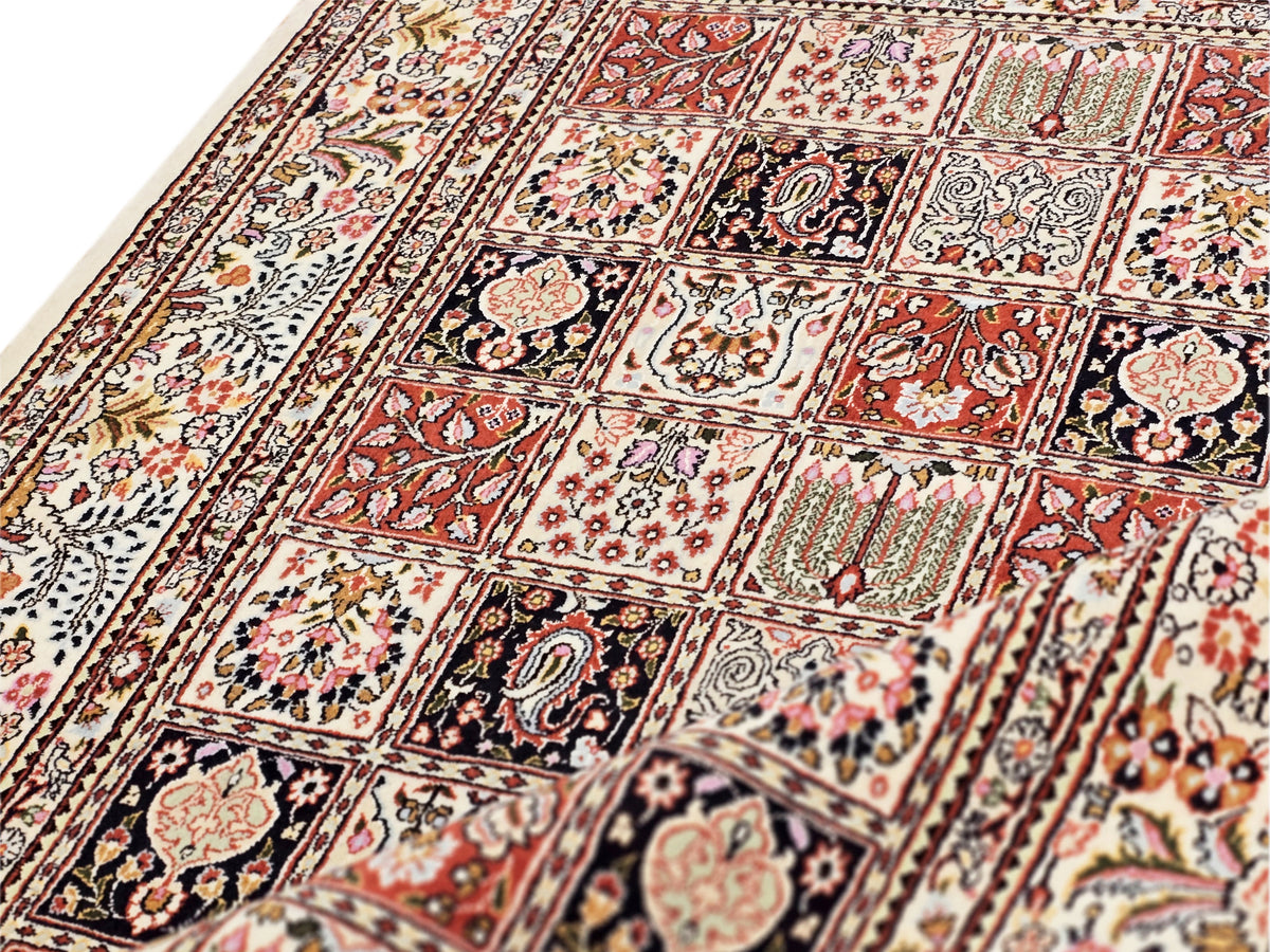 Close-up of multicolor tiled geometric rug with floral medallions and border strip.